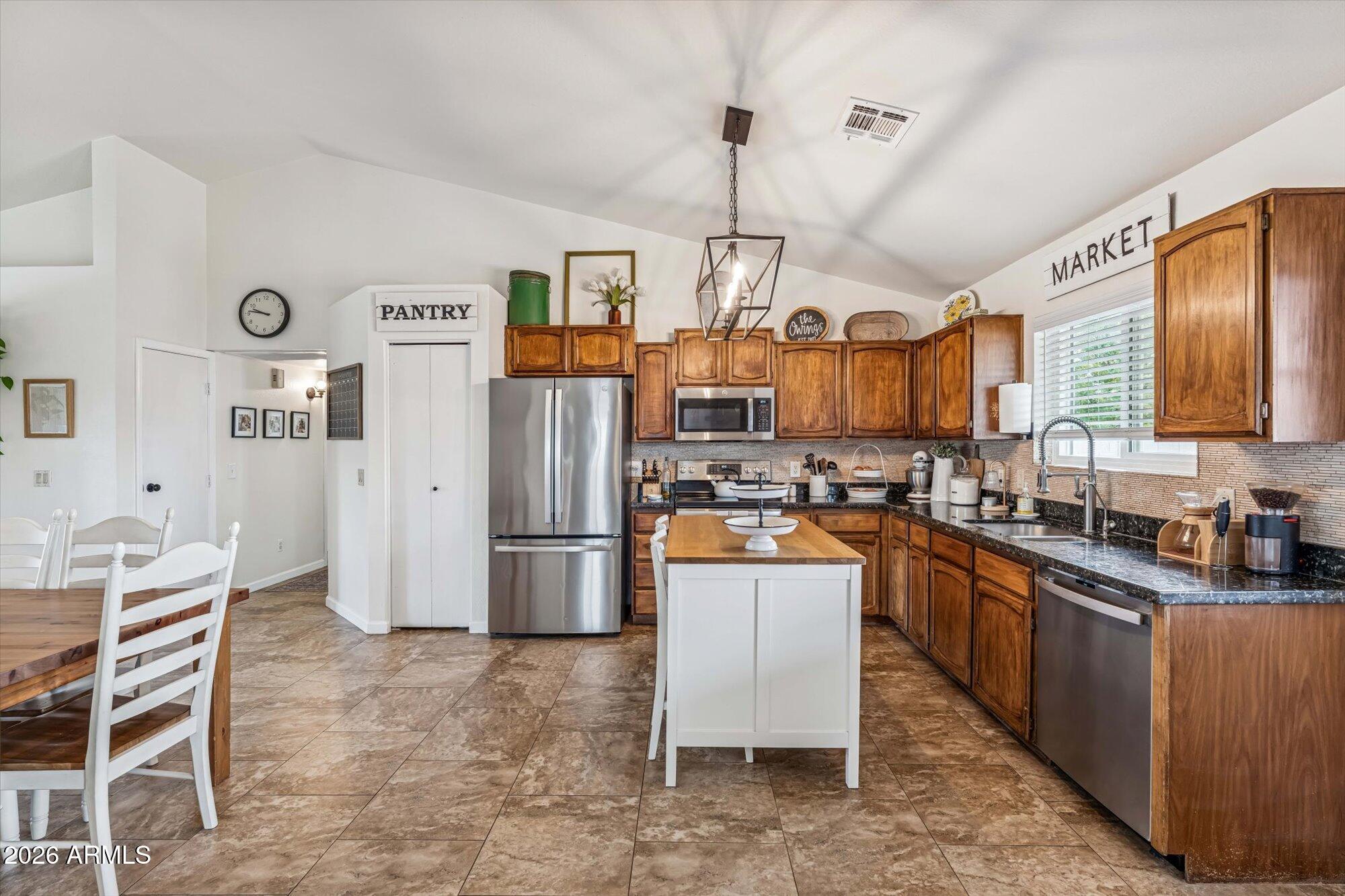 2019 East Butler Street Chandler, AZ 85225 - Photo 13 of 27 a kitchen with stainless steel appliances a refrigerator a stove a sink dishwasher and a dining table with wooden floor