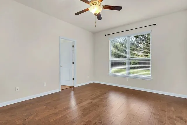 a view of an empty room with wooden floor and a window