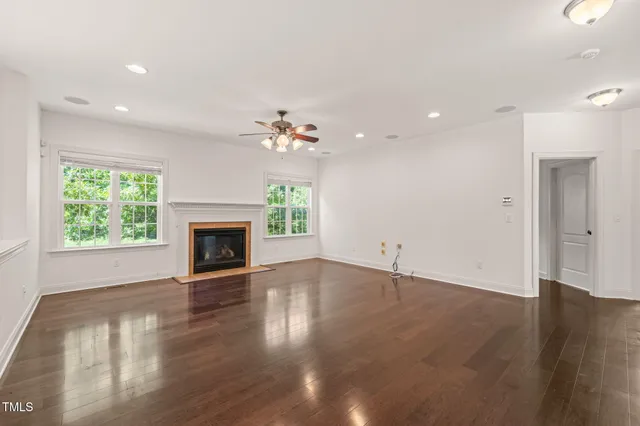 an empty room with wooden floor fireplace and window