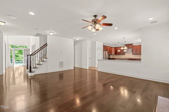 a view of an empty room with wooden floor and a ceiling fan