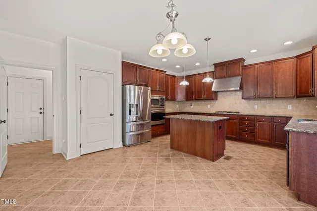 a large kitchen with stainless steel appliances kitchen island granite countertop a stove refrigerator and cabinets