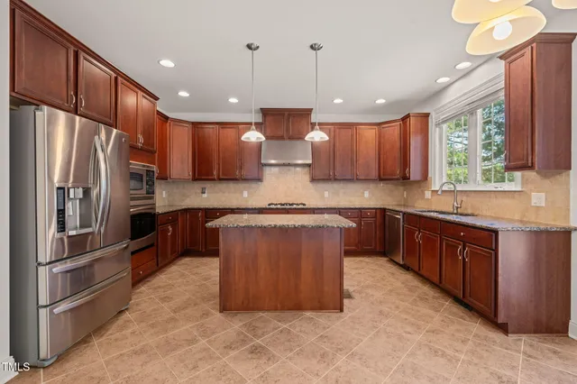 a large kitchen with stainless steel appliances kitchen island granite countertop a refrigerator a sink and a stove