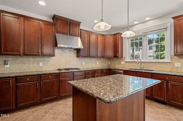 a kitchen with granite countertop kitchen island stainless steel appliances a sink stove and cabinets