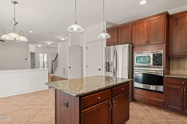 a kitchen with stainless steel appliances granite countertop a refrigerator a oven and a sink with cabinets