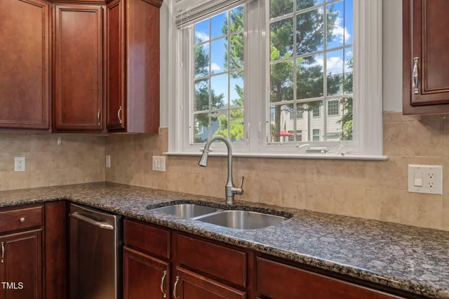 a kitchen with granite countertop a sink window and cabinets