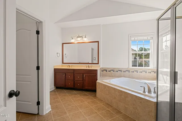 a spacious bathroom with a tub sink and mirror