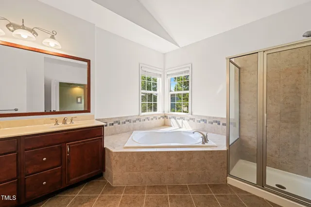a spacious bathroom with a tub sink and mirror