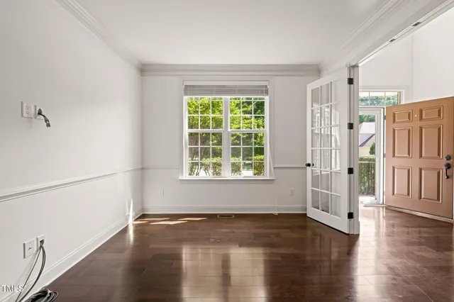 a view of an empty room with a window and wooden floor
