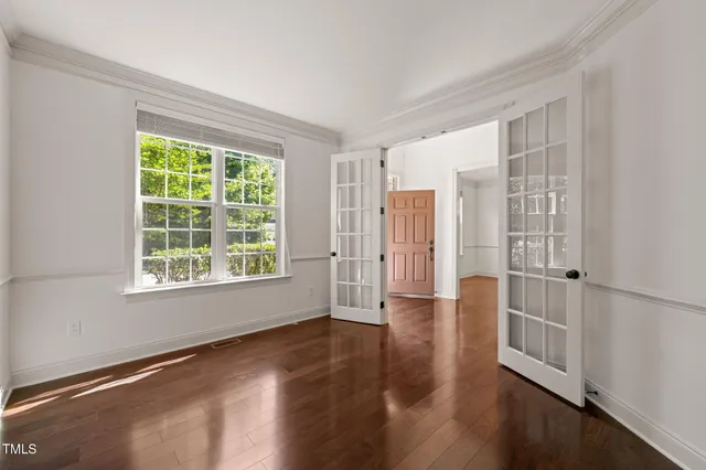 a view of an empty room with wooden floor and a window