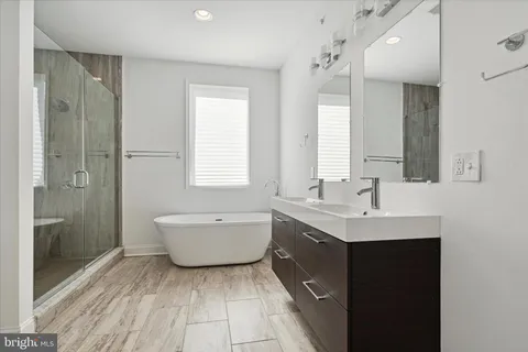 a bathroom with a double vanity sink mirror and bathtub
