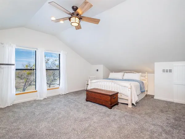 a spacious bedroom with a bed painting on wall and a large window