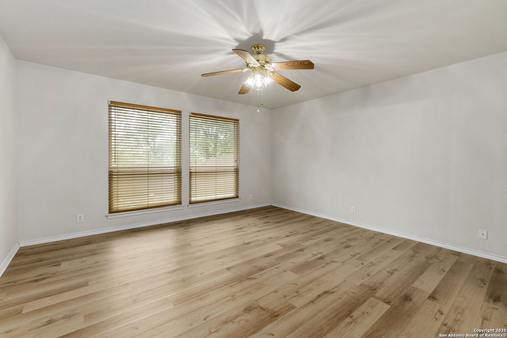 15311 Spring Rock San Antonio, TX 78247 - Photo 17 of 32 an empty room with wooden floor chandelier fan and windows