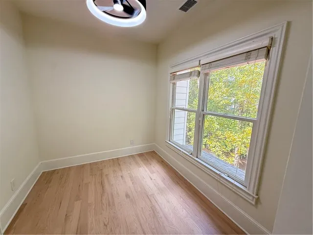 an empty room with windows a fireplace a ceiling fan and wooden floor