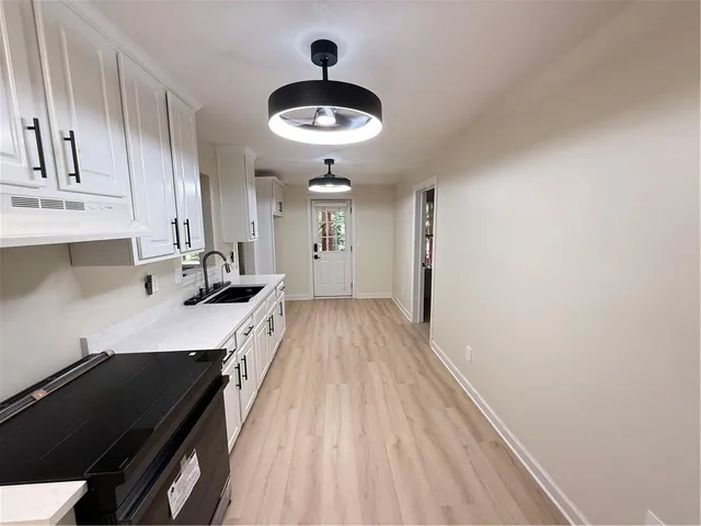 a kitchen with granite countertop a sink cabinets and stainless steel appliances
