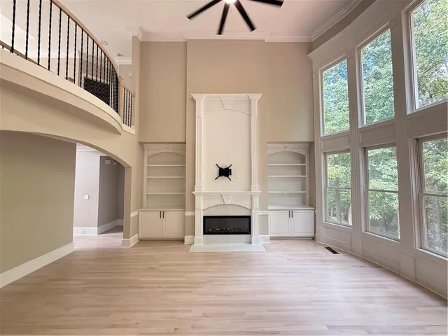 a view of an empty room with wooden floor and windows