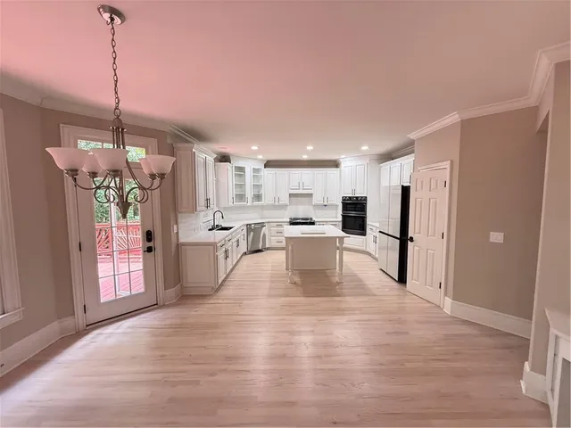 a view of a kitchen with a refrigerator a window and a wooden floor