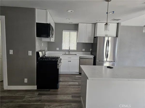 a kitchen with granite countertop a refrigerator and a stove top oven