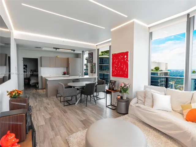 a living room with furniture kitchen view and a large window