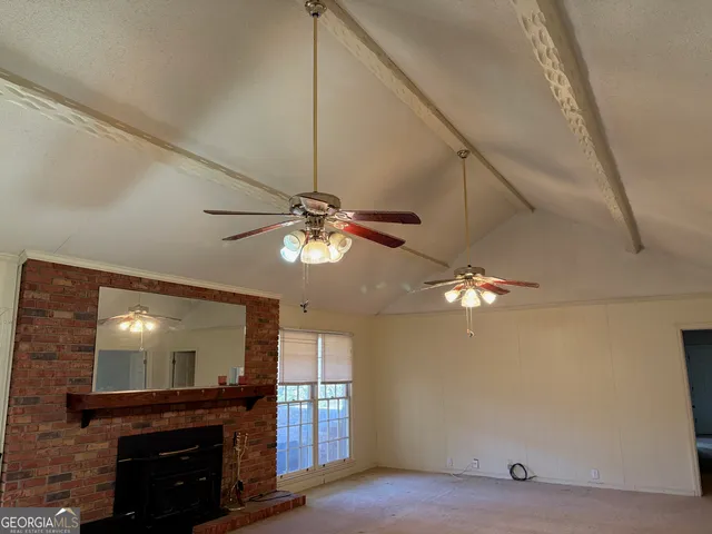 a view of a livingroom with a fireplace a ceiling fan and wooden floor
