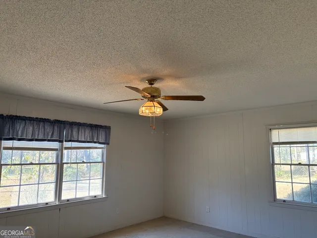 an empty room with windows and chandelier fan