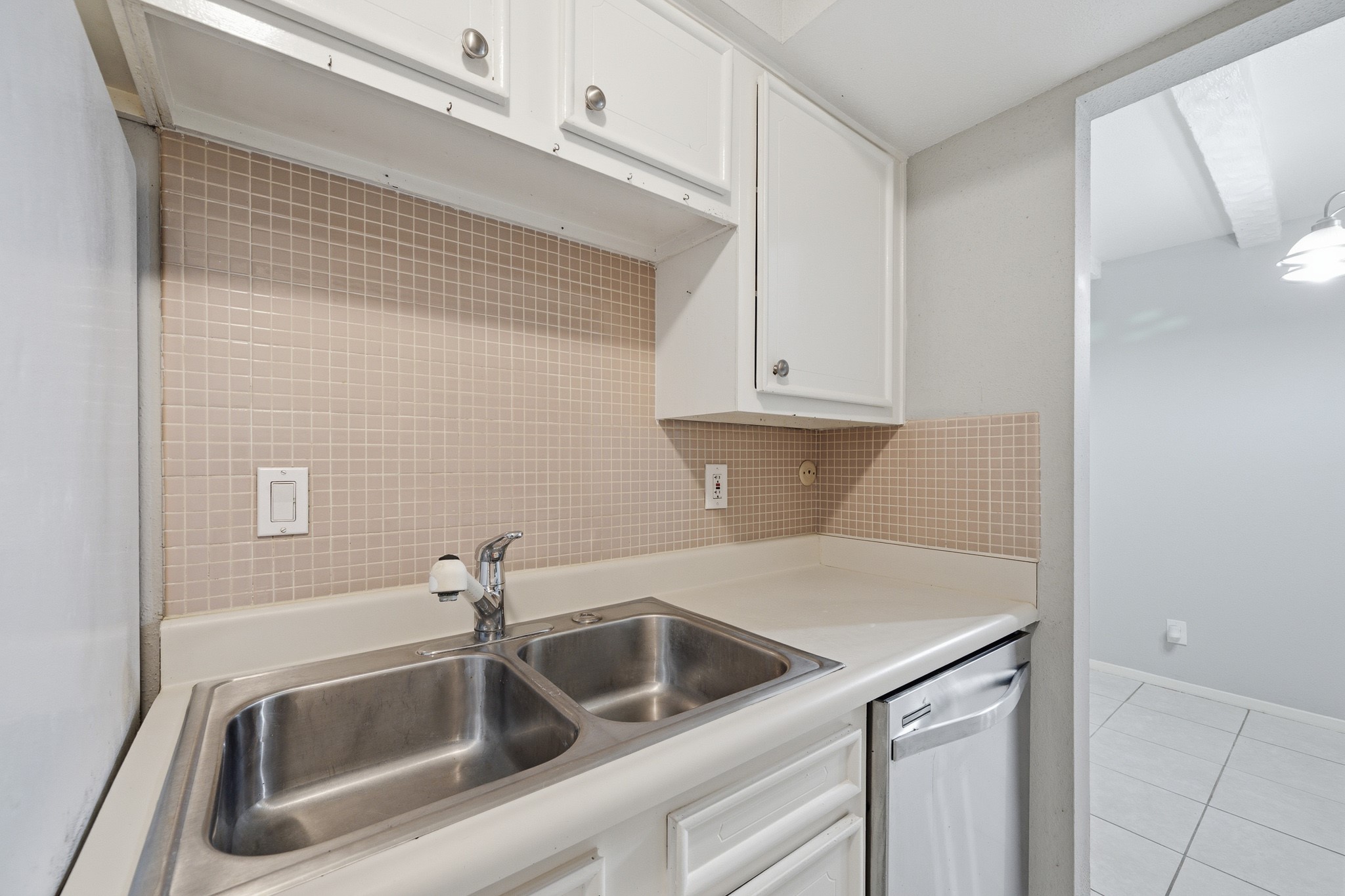 11550 Chimney Rock Road, Unit 133 Houston, TX 77035 - Photo 13 of 40 Kitchen offers a dual stainless steel sink, white cabinetry, and a neutral tile backsplash, offering a clean and functional space.