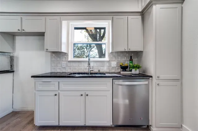 a kitchen with stainless steel appliances granite countertop white cabinets a window and a sink
