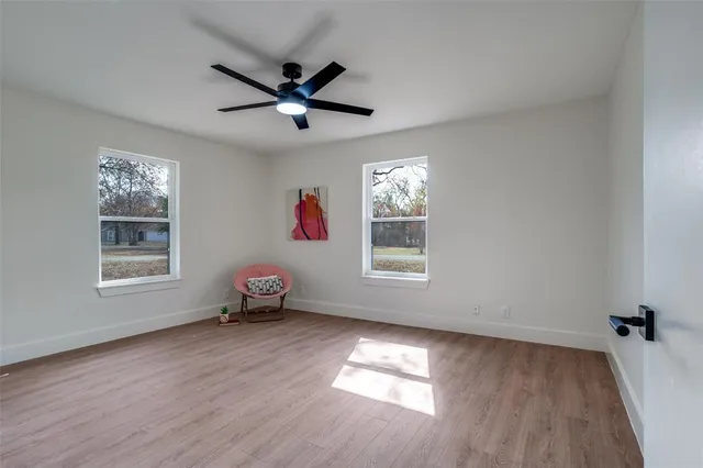 a view of empty room with wooden floor and fan