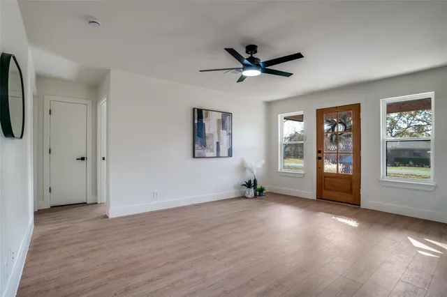 a view of empty room with wooden floor and fan
