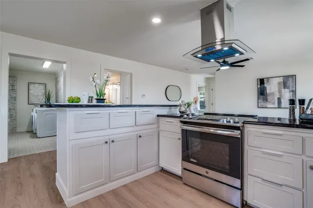 a kitchen with stainless steel appliances a stove a sink and white cabinets with wooden floor