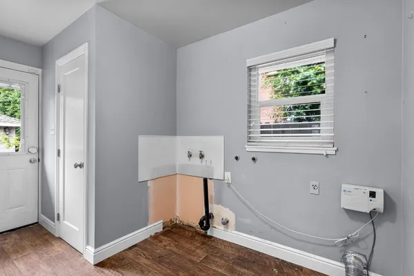 a view of hallway with window and wooden floor