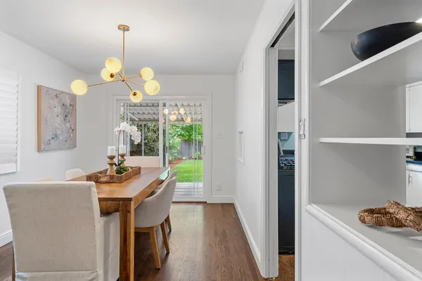 a dining room with wooden floor a chandelier a wooden table and chairs
