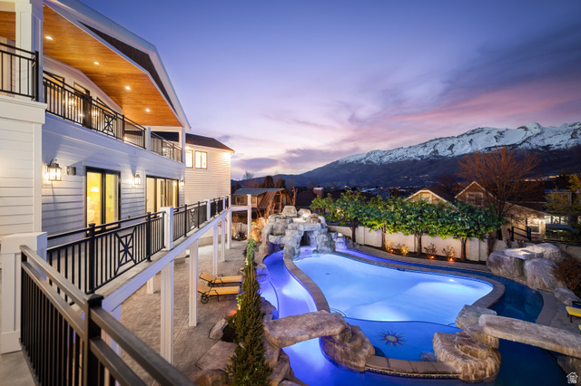 1263 Chapman Court Alpine, UT 84004 - Photo 11 of 83 Pool at dusk featuring a patio, a mountain view, and a fenced backyard