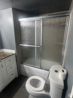 8155 South Redwood Road, Unit 96 West Jordan, UT 84088 - Photo 15 of 17 Bathroom featuring vanity, dark tile patterned floors, and bath / shower combo with glass door