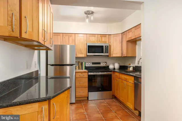 a kitchen with stainless steel appliances granite countertop a refrigerator a stove top oven and a sink