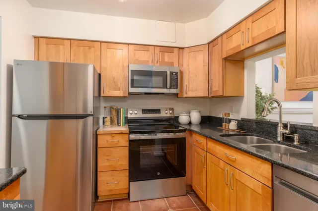 a kitchen with stainless steel appliances granite countertop a refrigerator a stove a sink and a microwave