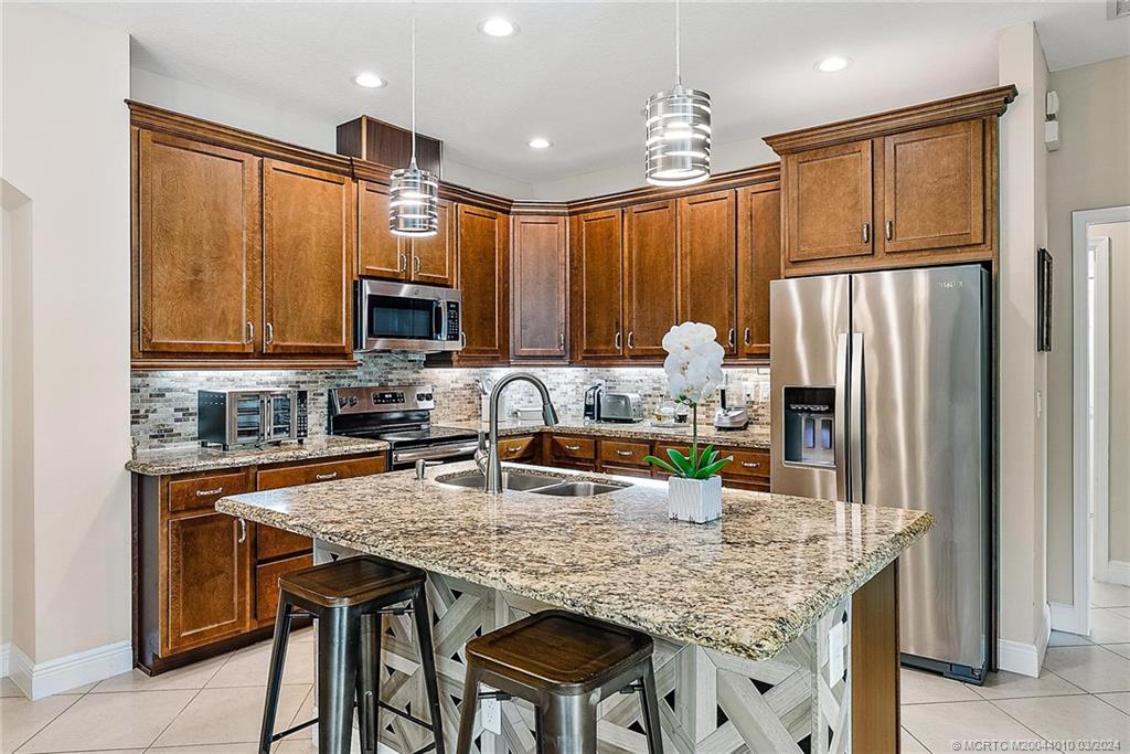 a kitchen with granite countertop a table chairs microwave and refrigerator