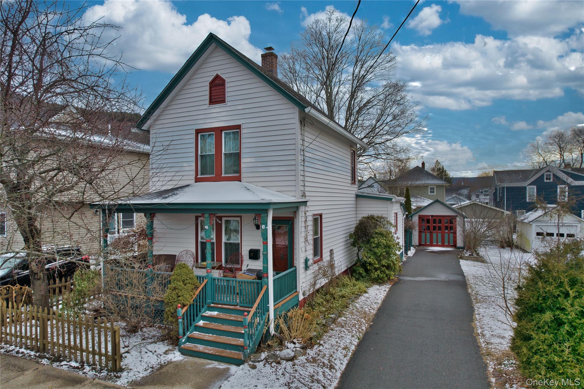 View of front facade featuring an outdoor structure, covered porch, a chimney, and a garage