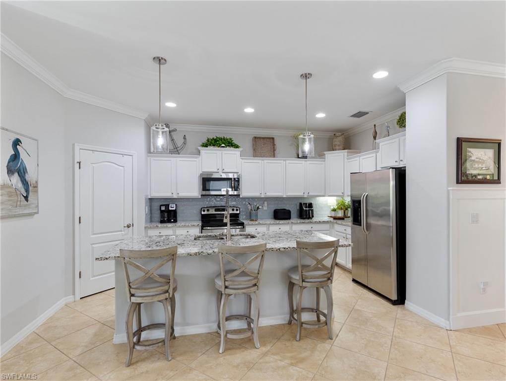21116 Bella Terra Boulevard Estero, FL 33928 - Photo 15 of 49 a kitchen with stainless steel appliances kitchen island granite countertop a refrigerator a stove a sink a dining table and chairs
