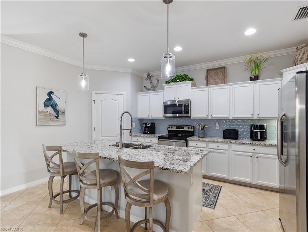 21116 Bella Terra Boulevard Estero, FL 33928 - Photo 16 of 49 a kitchen with stainless steel appliances kitchen island granite countertop a dining table and chairs