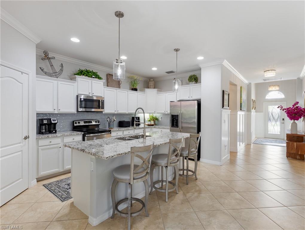 21116 Bella Terra Boulevard Estero, FL 33928 - Photo 17 of 49 a kitchen with stainless steel appliances kitchen island granite countertop a sink a stove a refrigerator and cabinets