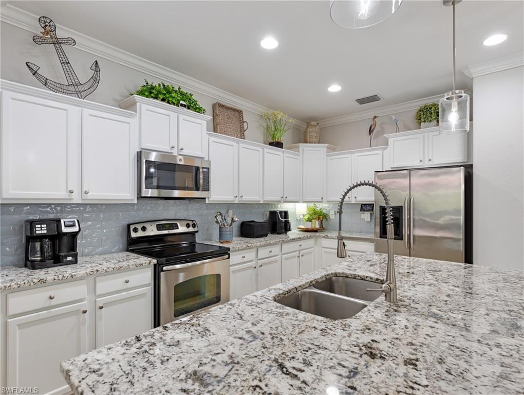 21116 Bella Terra Boulevard Estero, FL 33928 - Photo 18 of 49 a kitchen with granite countertop a sink stainless steel appliances and white cabinets