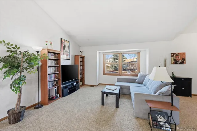 a living room with furniture a bookshelf and a flat screen tv