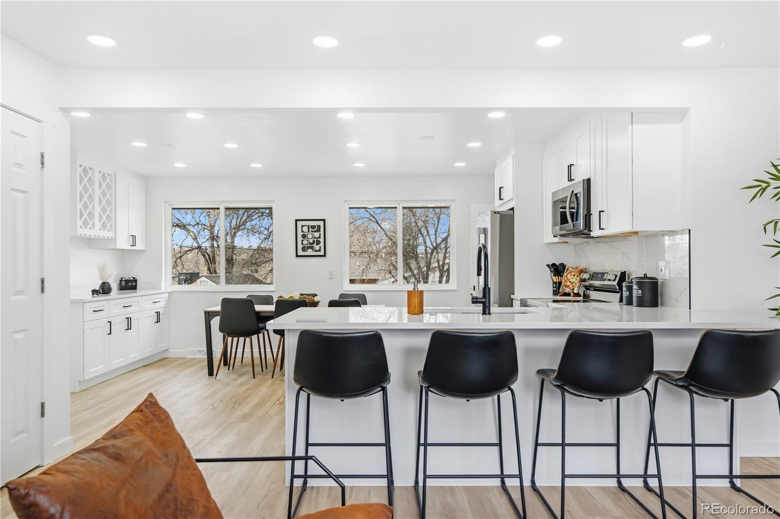 a kitchen with stainless steel appliances kitchen island granite countertop a dining table chairs and a white cabinets