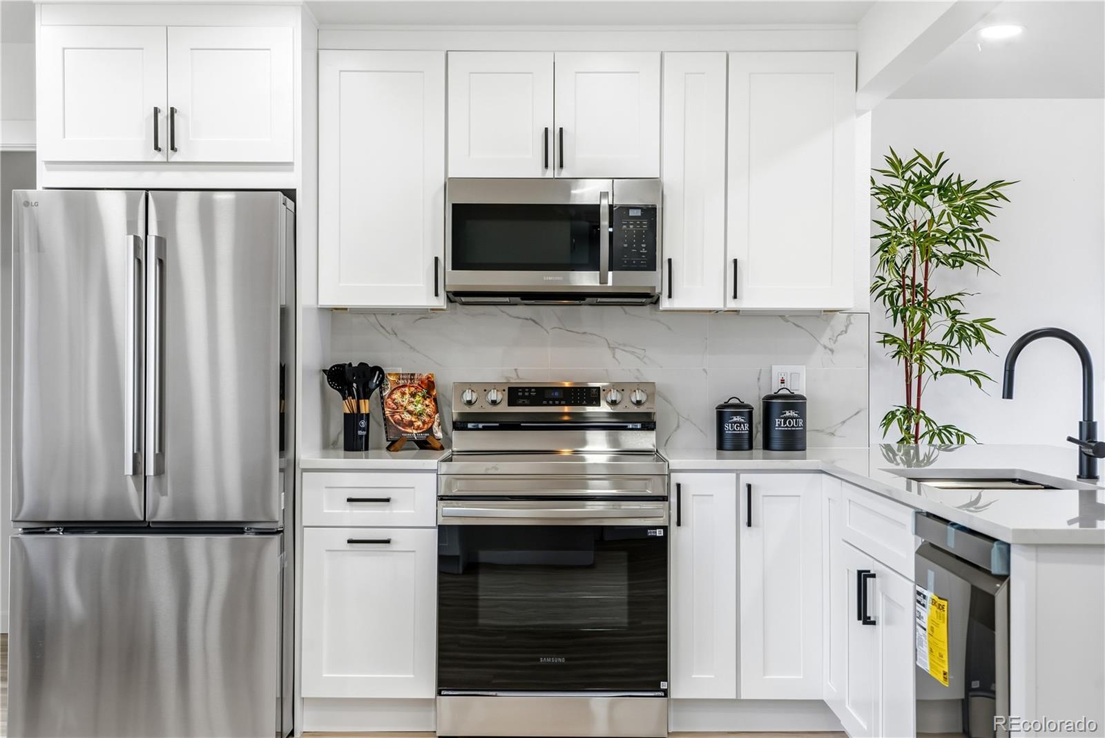 8331 Ogden Street Denver, CO 80229 - Photo 4 of 23 a kitchen with stainless steel appliances white cabinets and a stove
