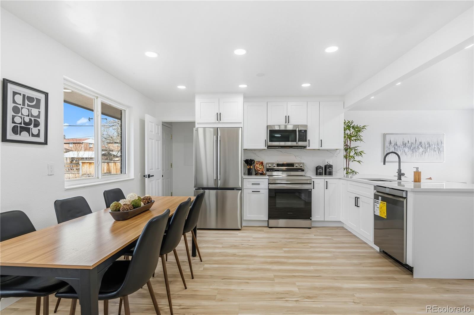 8331 Ogden Street Denver, CO 80229 - Photo 5 of 23 a kitchen with stainless steel appliances granite countertop a stove top oven a refrigerator a kitchen island and couches with wooden floor