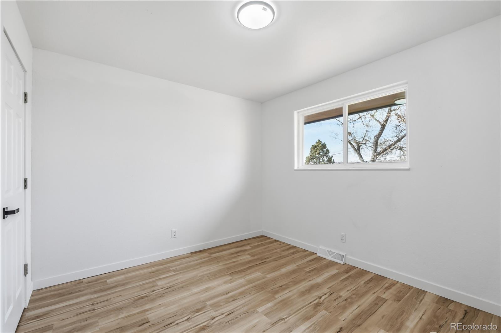 8331 Ogden Street Denver, CO 80229 - Photo 9 of 23 an empty room with wooden floor and window