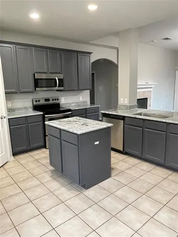 a kitchen with stainless steel appliances granite countertop a stove top oven a sink dishwasher and a refrigerator