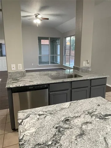 a kitchen with a granite countertop sink and dishwasher