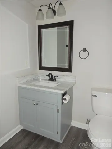 a bathroom with a toilet sink vanity and mirror