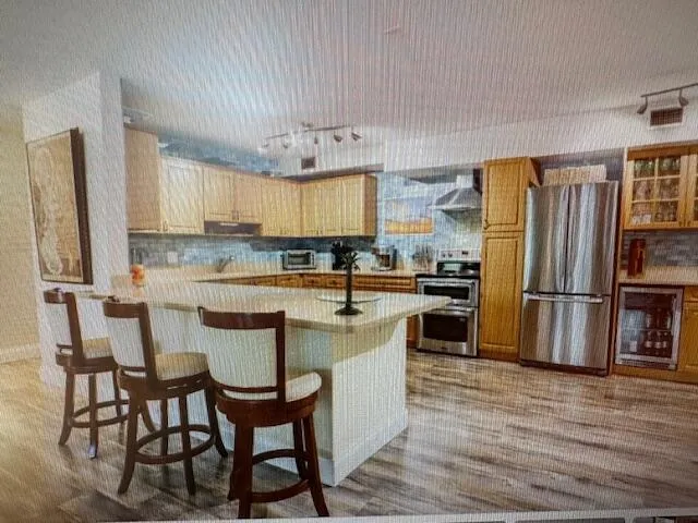 a kitchen with stainless steel appliances a dining table chairs refrigerator and sink